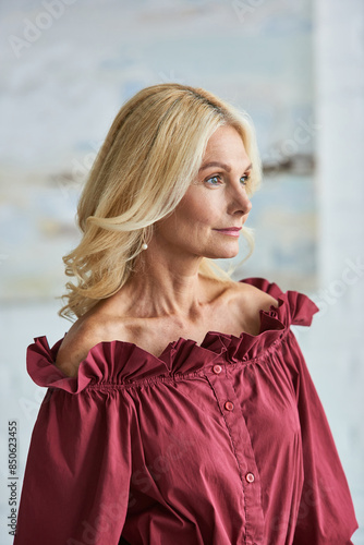 A mature woman with blonde hair in a stylish red blouse.