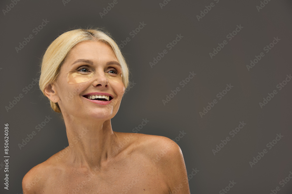 Appealing mature woman with blonde hair with eye patches on a gray backdrop. Appealing mature woman with blonde hair with eye patches on a gray backdrop.