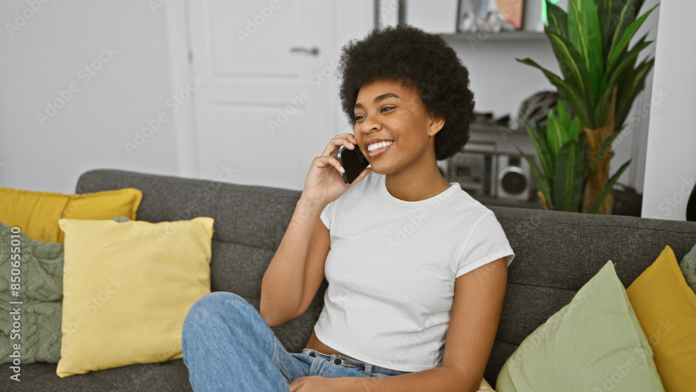 Smiling african american woman enjoying a phone conversation while relaxing on a couch at home Smiling african american woman enjoying a phone conversation while relaxing on a couch at home