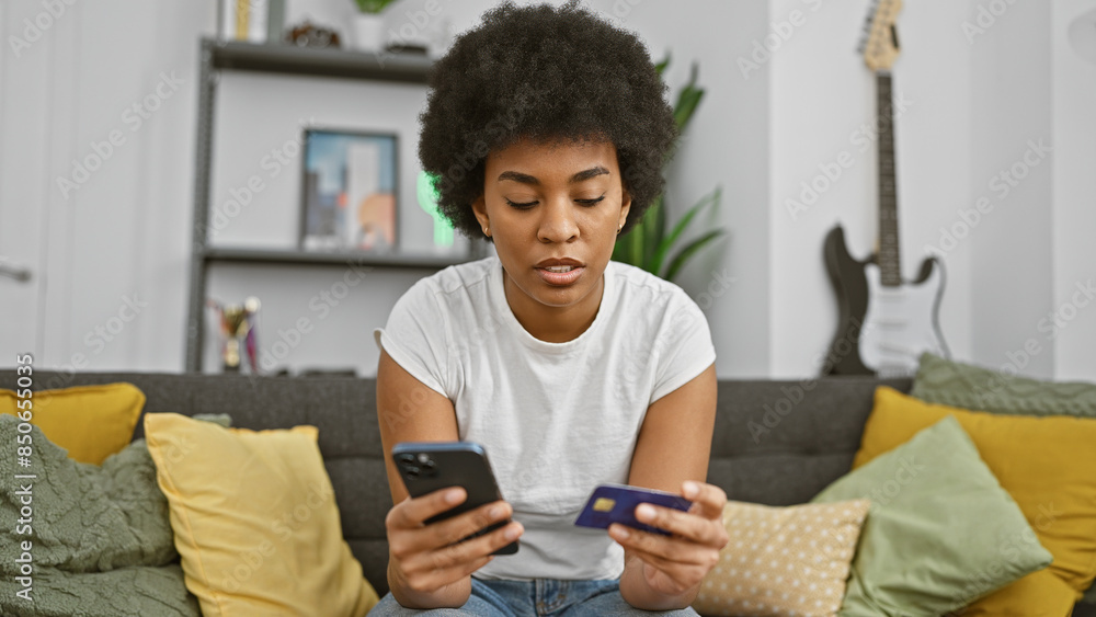 African american woman using a smartphone and credit card for online shopping at home. African american woman using a smartphone and credit card for online shopping at home.