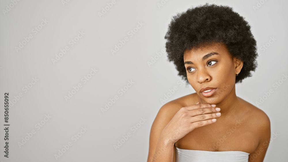 A thoughtful african american woman with curly hair posed against a white background, exuding elegance and contemplation. A thoughtful african american woman with curly hair posed against a white background, exuding elegance and contemplation.