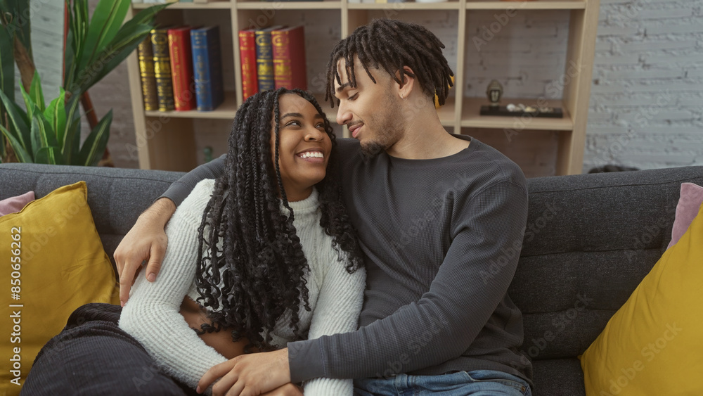 A man and woman in a loving embrace sit on a sofa in a cozy living room with books and decor A man and woman in a loving embrace sit on a sofa in a cozy living room with books and decor