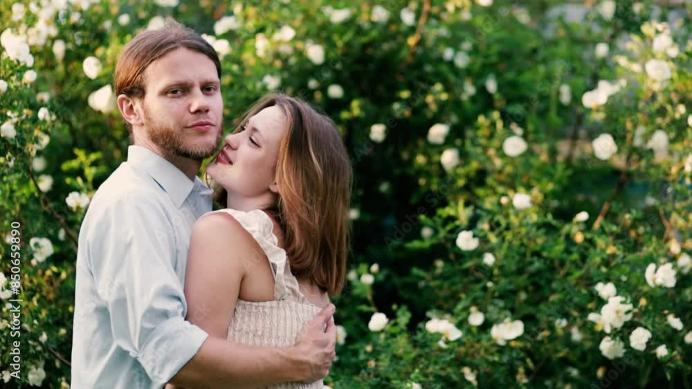 beautiful couple in retro clothes hugging near a tree of white roses in the summer in the village. beautiful couple in retro clothes hugging near a tree of white roses in the summer in the village.