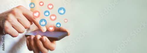 Social media and digital online communication concept, man using smartphone with likes icons on social media. Banner background. photo