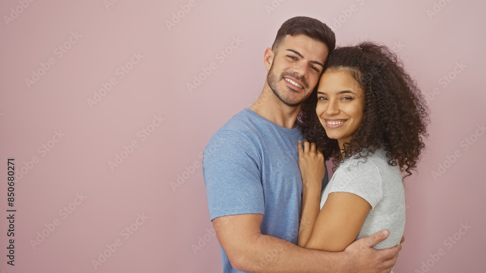 Affectionate man and woman hugging, smiling against a plain pink background, depicting love and togetherness. Affectionate man and woman hugging, smiling against a plain pink background, depicting love and togetherness.