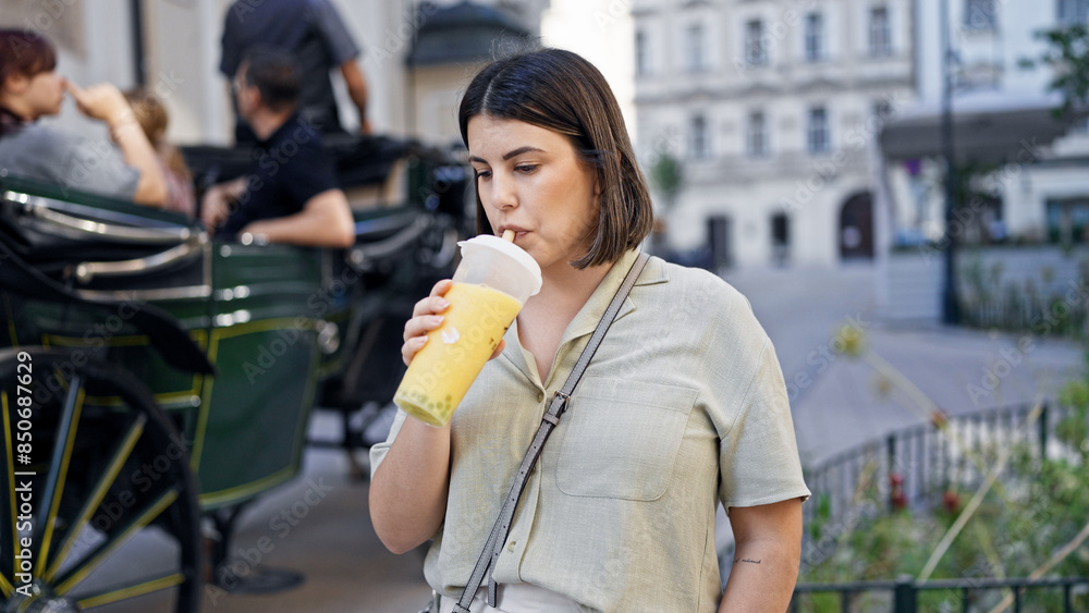 Fototapeta premium Young beautiful hispanic woman drinking bubble tea in the streets of Vienna