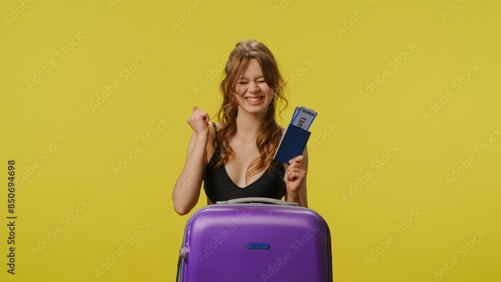 Young woman in swimsuit with suitcase poses with flight tickets, excited expression. Travel, summertime vacation, leisure concept. Young woman in swimsuit with suitcase poses with flight tickets, excited expression. Travel, summertime vacation, leisure concept.