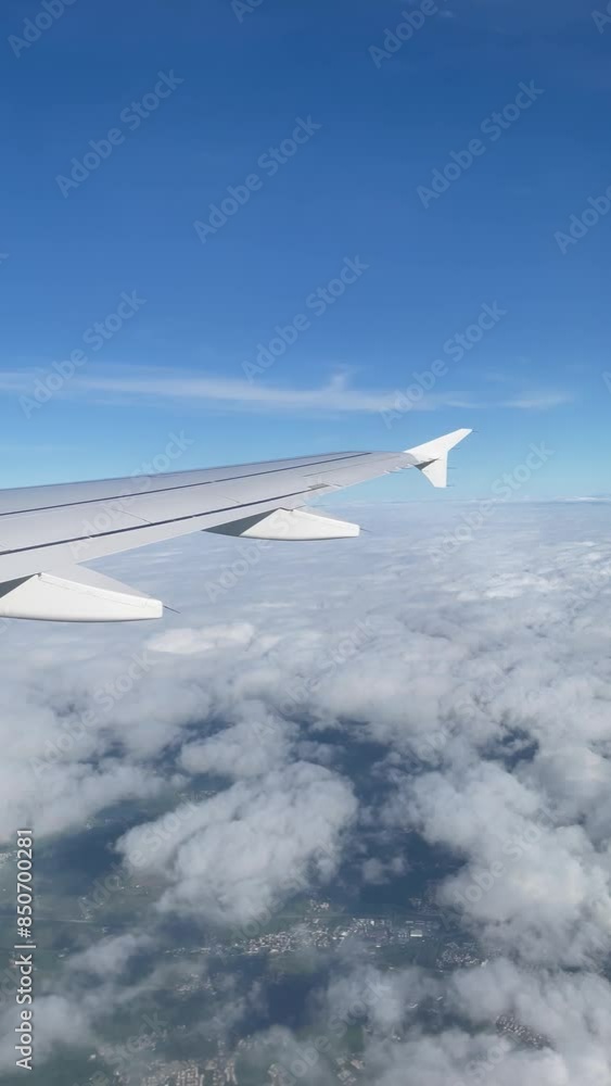 Airplane wing view flying above fluffy clouds on a clear day Airplane wing view flying above fluffy clouds on a clear day
