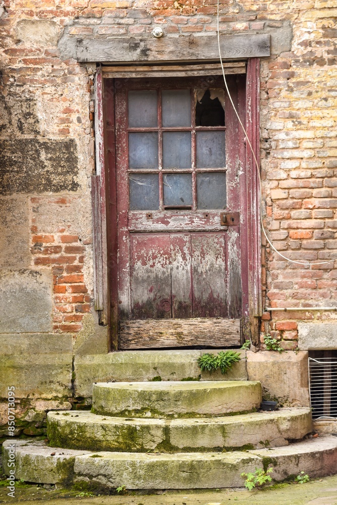 abandoned old reddish door with stone steps in France