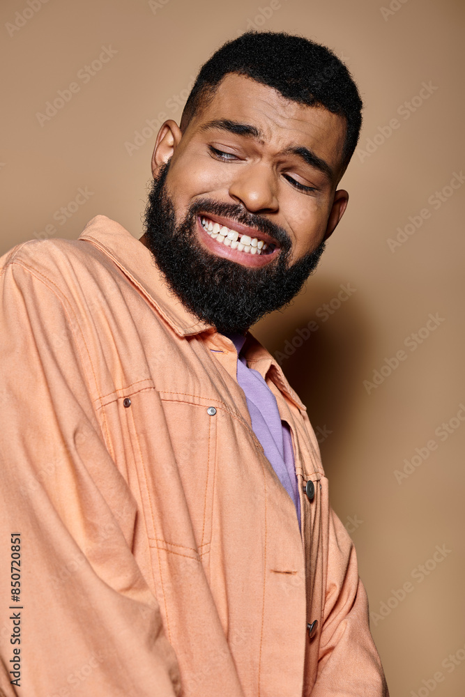 Obraz premium Stylish man with beard smiling in trendy orange attire.
