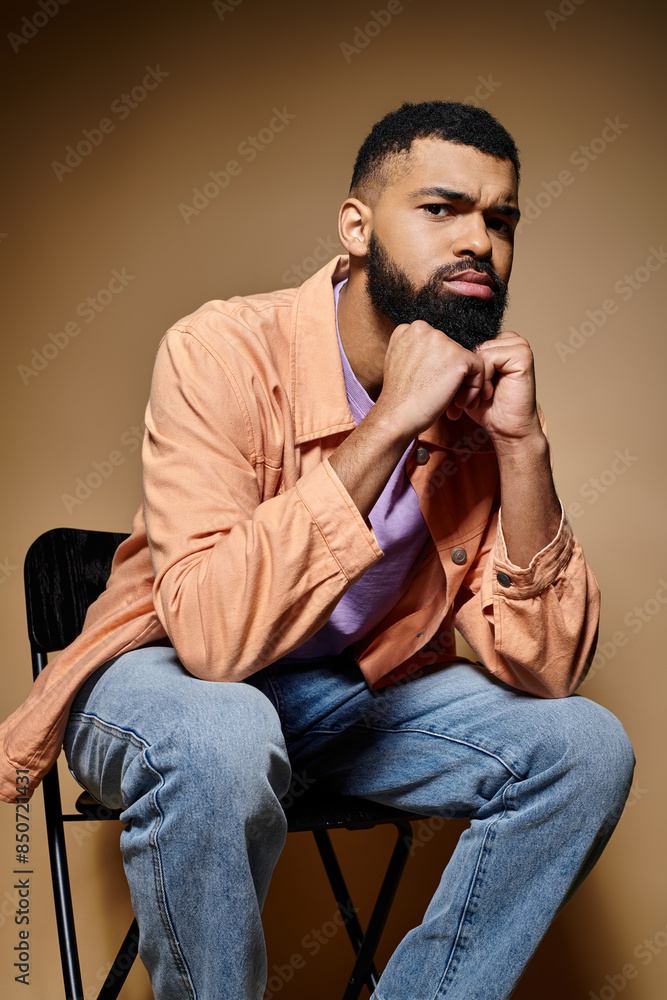 A stylish African American man with a beard sitting gracefully on a chair. A stylish African American man with a beard sitting gracefully on a chair.