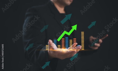 Person using a smartphone with a holographic display showing business growth charts and arrows. Represents virtual analytics, technology, and financial progress.
