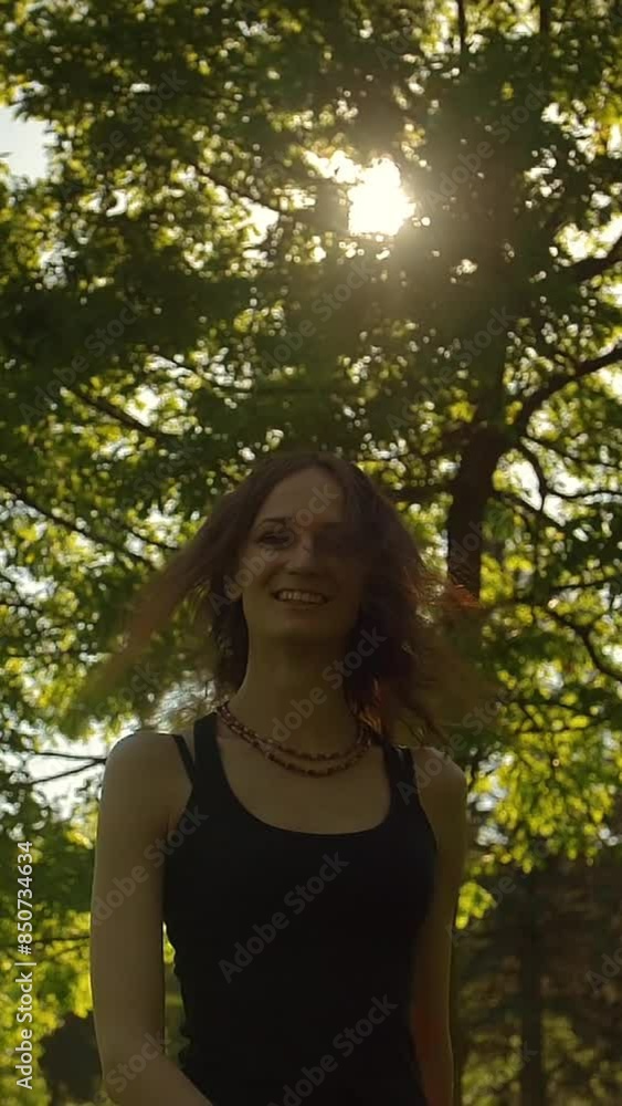 Attractive handsome young woman with long wavy red ginger hair is run and jump in forest in summer day, turn to a camera.Super slow motion. Sunset Vertical shot. Attractive handsome young woman with long wavy red ginger hair is run and jump in forest in summer day, turn to a camera.Super slow motion. Sunset Vertical shot.