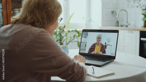 Wallpaper Mural Senior woman sitting at kitchen table, waving and chatting with African American female friend via video call on laptop during day at home Torontodigital.ca