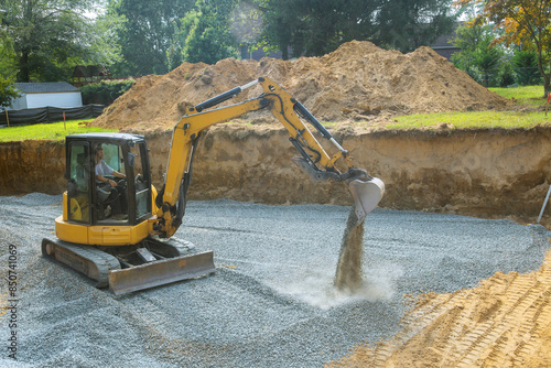 On construction site, an excavator fills irregularities in excavations with granite rubble base, which will be used for concrete foundation photo