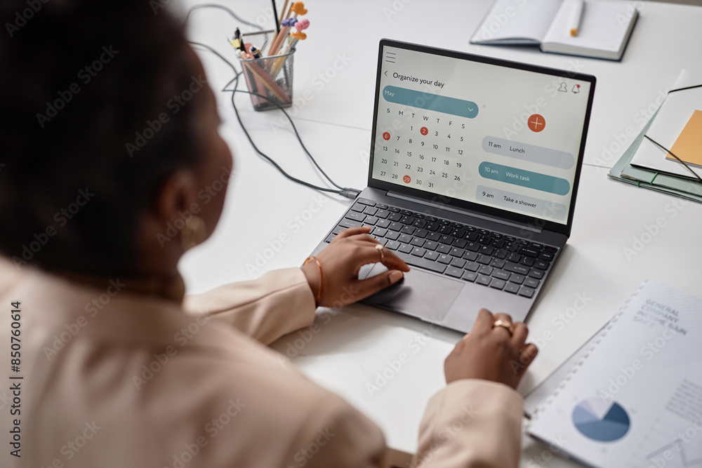 © Seventyfour - African American female in office working on laptop displaying calendar page with daily tasks. Over shoulder close up, focus on screen, copy space © Seventyfour - African American female in office working on laptop displaying calendar page with daily tasks. Over shoulder close up, focus on screen, copy space