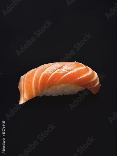 This is a photo of a piece of sushi with salmon on top. The salmon is orange and the rice is white. The sushi is sitting on a black background.