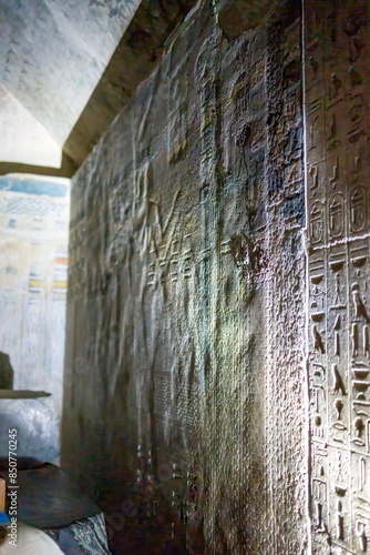 Hieroglyphs inside an Egyptian tomb with a relief scene carved and revealed with shadowed light