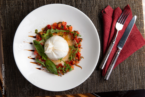 Buratta cheese with tomato and arugula in a plate.