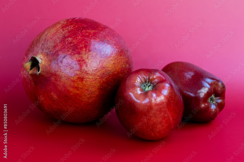 Ripe red apples and pomegranate on a pink background Ripe red apples and pomegranate on a pink background