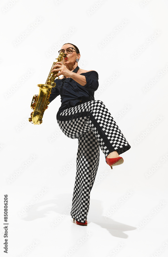 Fototapeta premium Dynamic image of elegant woman, stylish saxophonist playing saxophone with soul and energy isolated on white background. Concept of music, festival, concert, hobby, talent, performance