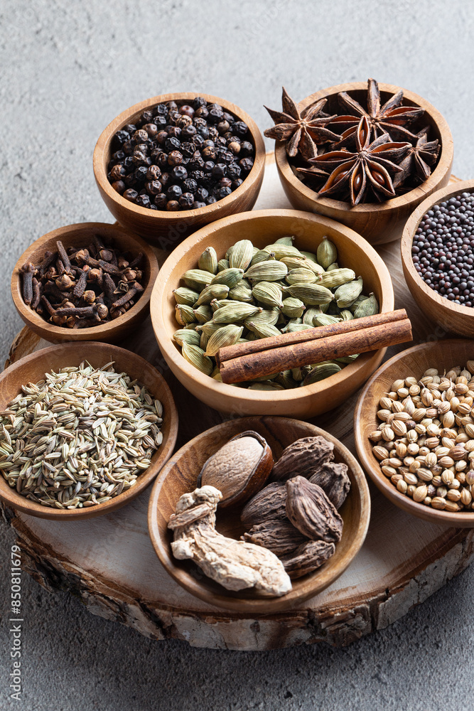 Set of various whole warming Indian spices in wooden bowls on a gray background vertical Set of various whole warming Indian spices in wooden bowls on a gray background vertical