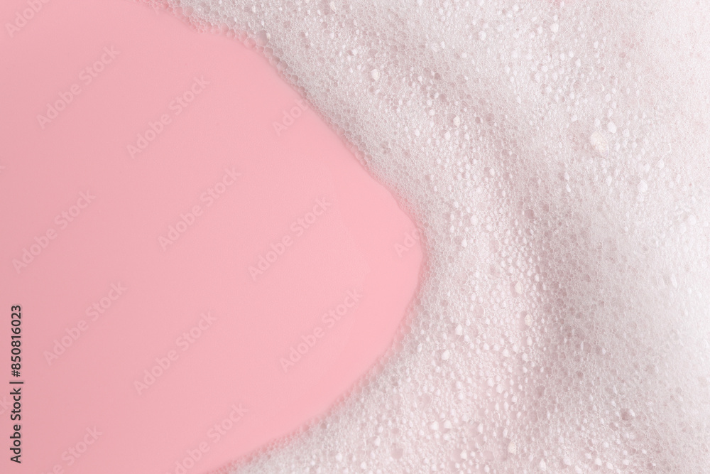 Fototapeta premium White fluffy foam on pink background, top view. Space for text