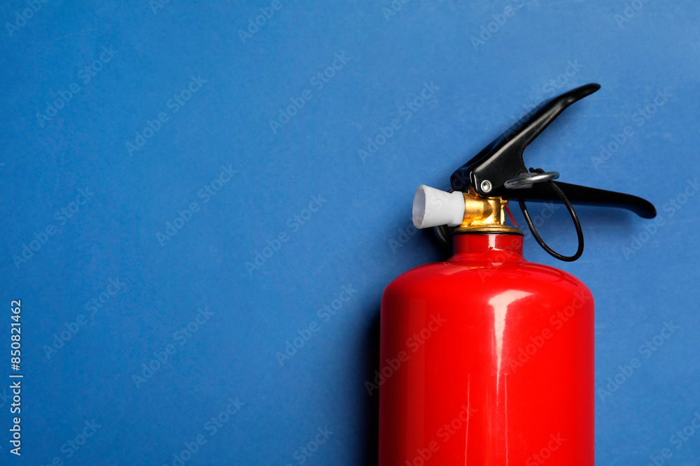 One red fire extinguisher on blue background, top view. Space for text One red fire extinguisher on blue background, top view. Space for text