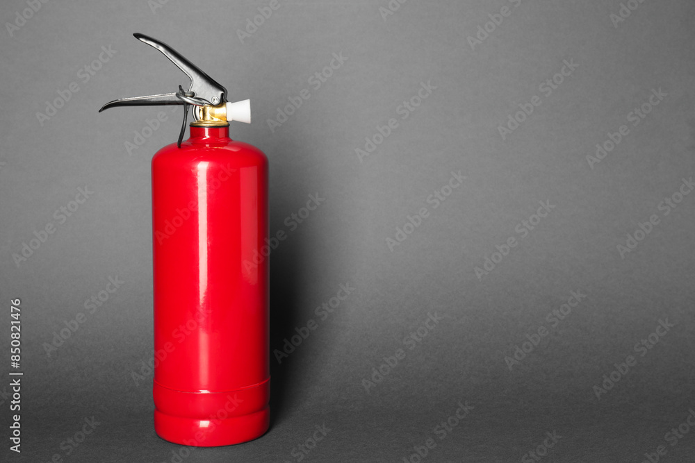 One red fire extinguisher on gray background, space for text One red fire extinguisher on gray background, space for text