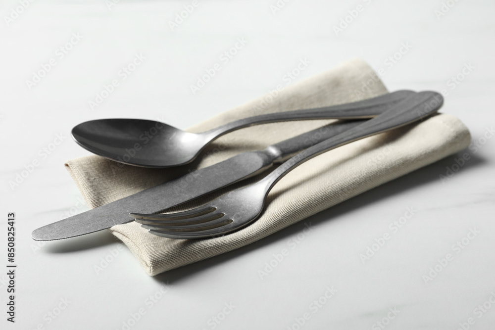 Stylish cutlery set and napkin on white table Stylish cutlery set and napkin on white table
