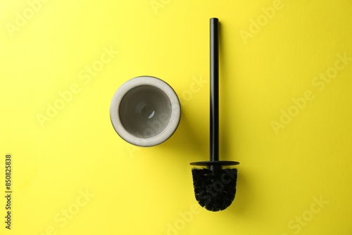 Toilet brush and holder on yellow background, top view