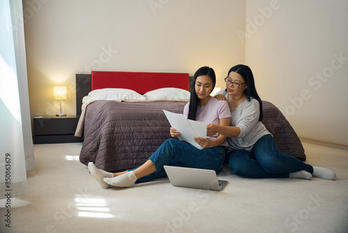 Family of two looking through documentation in bedroom in morning