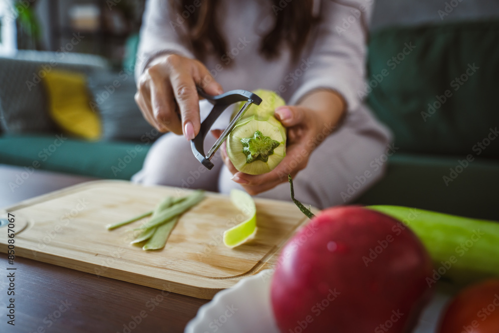 Unknown adult caucasian woman sit on sofa and peel zucchini Unknown adult caucasian woman sit on sofa and peel zucchini