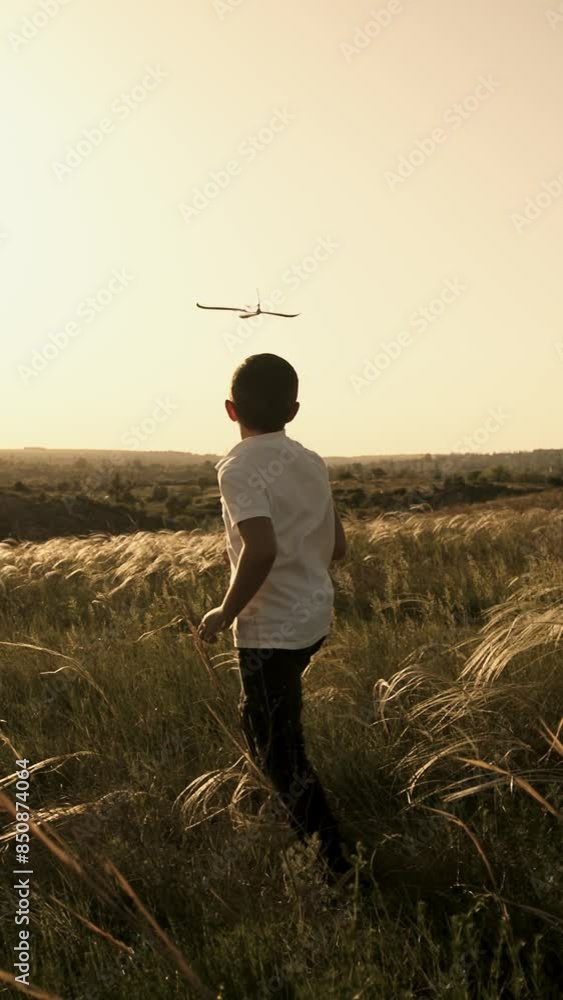 Vertical video. A happy boy runs with a toy airplane across a field in the rays of the sun. Children play with a toy airplane in the countryside. A teenager dreams of flying and becoming a pilot. Vertical video. A happy boy runs with a toy airplane across a field in the rays of the sun. Children play with a toy airplane in the countryside. A teenager dreams of flying and becoming a pilot.