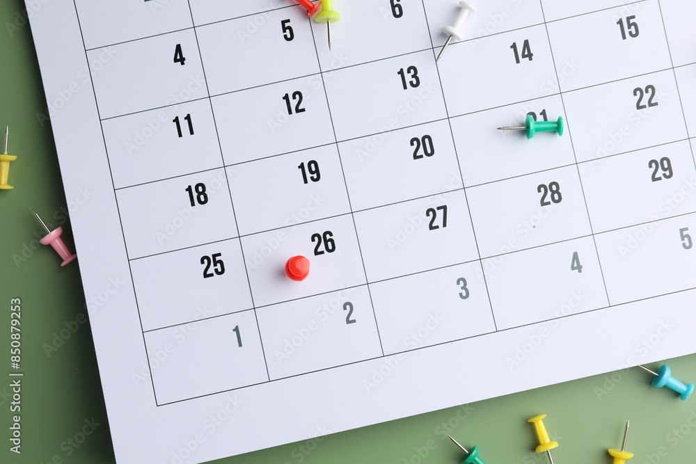 Timetable. Calendar and drawing pins on green background, top view Timetable. Calendar and drawing pins on green background, top view