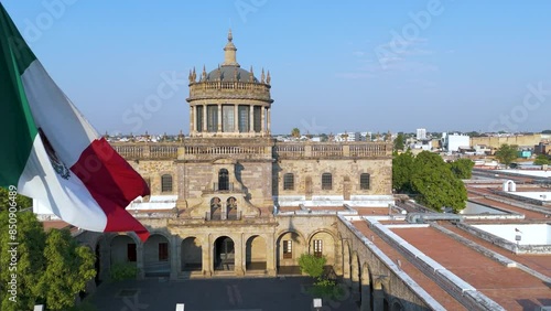 Aerial View of Hospicio Cabañas: Sunlit Museum in Historic Guadalajara with Mexican Flag and Locals Enjoying the Plaza