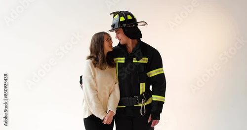 The fireman hugs the girl who is happy that he returned unharmed. Footage of a firefighter with a girl on a white background in the studio photo