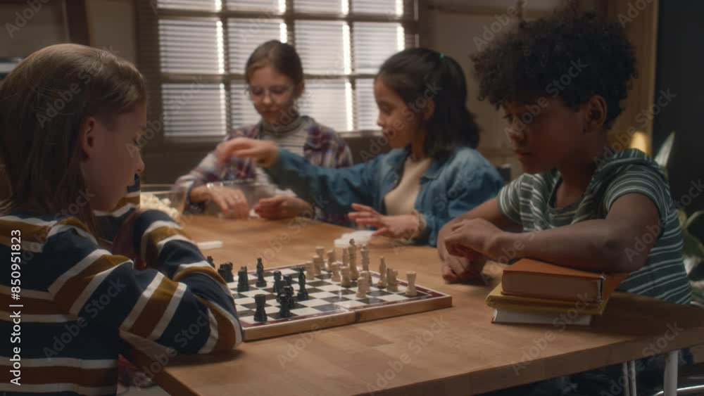 Side shot of young diverse opponents playing chess at board games club. Boy thinking out his next move Side shot of young diverse opponents playing chess at board games club. Boy thinking out his next move