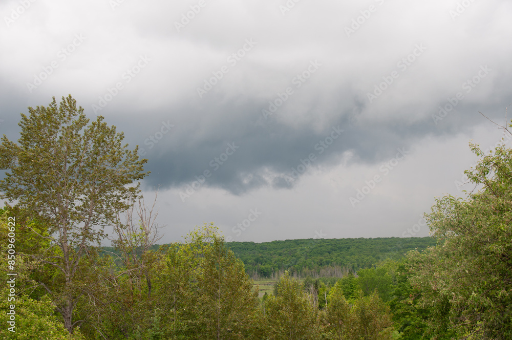 Obraz premium A gray cloud over a hilly forest in the spring