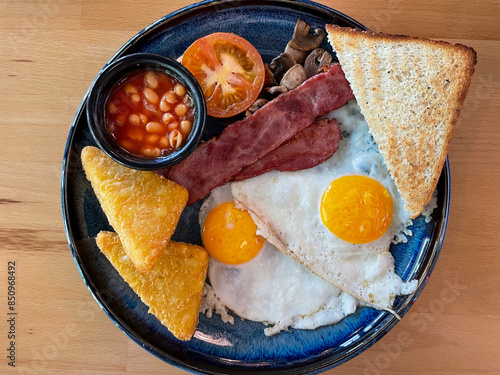 Photography Traditional English Irish breakfast with roasted eggs, bacon, tomatoes, white be
