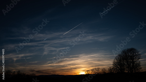 Three Contrails Streaking Across the Sky as the Sun Sets