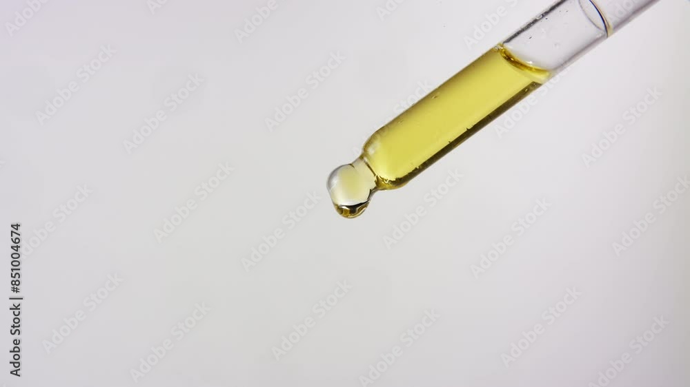 Close up of oil dropping from a dropper on isolated white background