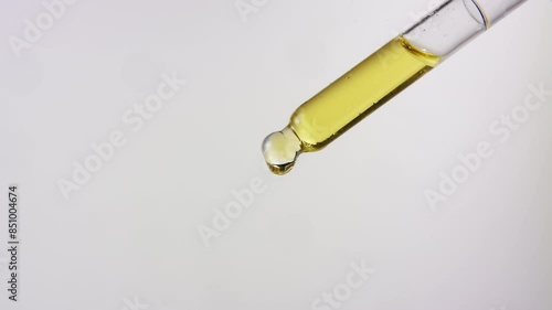 Close up of oil dropping from a dropper on isolated white background