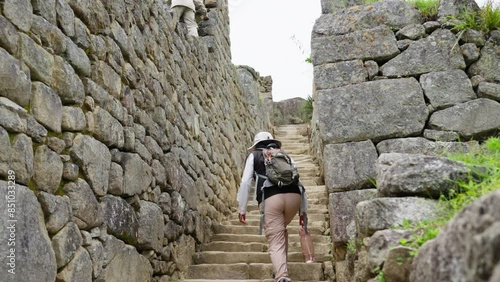 Tour Guide Climbing Stone Steps at Machu Picchu. Woman navigating the stone steps of Machu Picchu