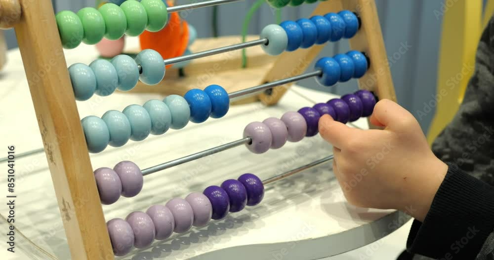 Child moves beads on abacus learning to count in kindergarten closeup. Little kid plays with tool improving motor skills and logical thinking development Child moves beads on abacus learning to count in kindergarten closeup. Little kid plays with tool improving motor skills and logical thinking development