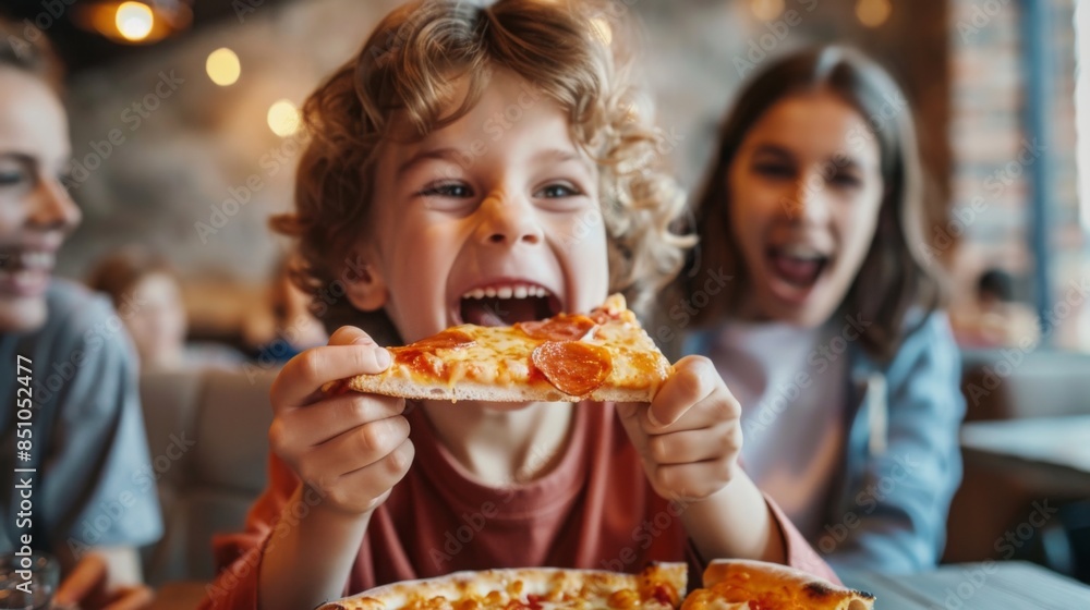 A young boy with curly hair happily eats a slice of pizza at a restaurant. He is smiling and enjoying his meal. A young boy with curly hair happily eats a slice of pizza at a restaurant. He is smiling and enjoying his meal.