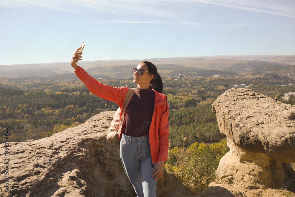 Young beautiful woman traveler taking selfie portrait on mountain top - Happy smiling girl using smartphone - Hiking and climbing rock