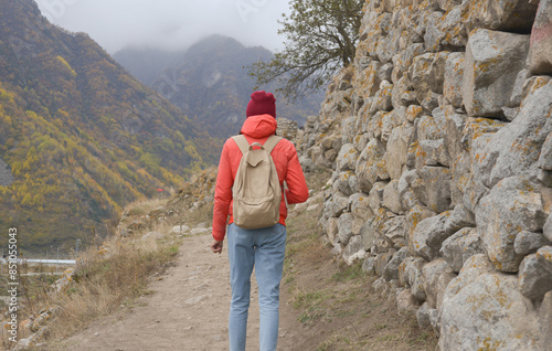A free woman traveler walks along paths in the mountains on a foggy autumn day. Adventure travel and success concept