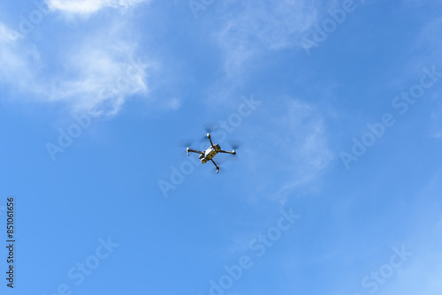 Drone performing capture in a sky with few clouds.