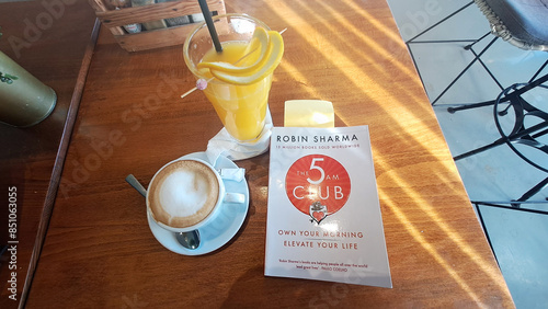 Slika na platnu Enjoying morning coffee and orange juice with bestselling self-help book by robi
